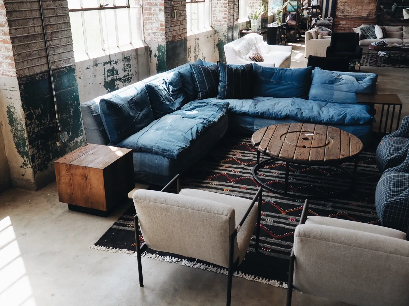 A loft space where a big sofa with cushions, a rug and armchairs dampen the echo