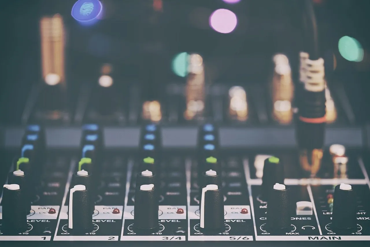Close-up of an analog mixer: channel faders, knobs, channel numbers and the MAIN bus