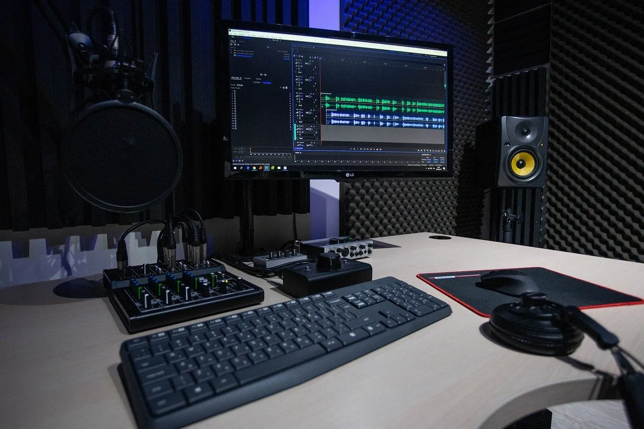 Home studio: a DAW on the computer screen, with a small mixer, an audio interface, a speaker and headphones on the desk