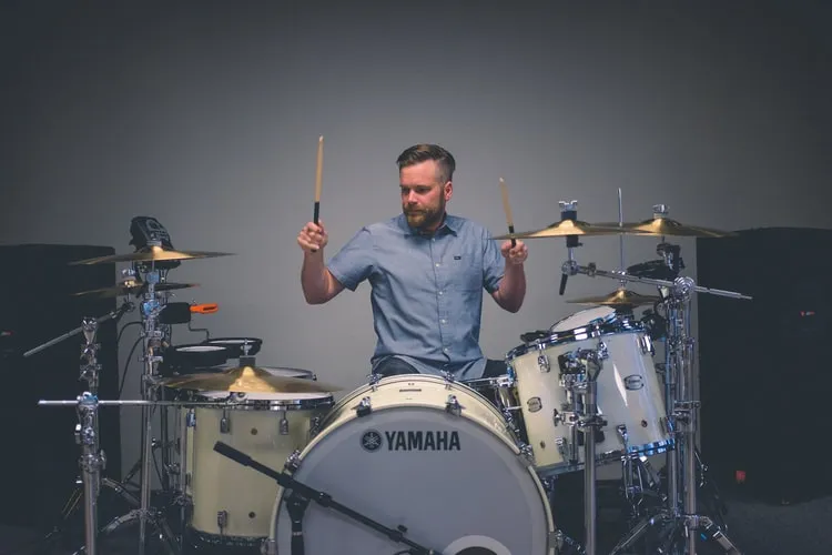Drummer playing a Yamaha drum kit against a calm gray background, nothing distracting in the shot