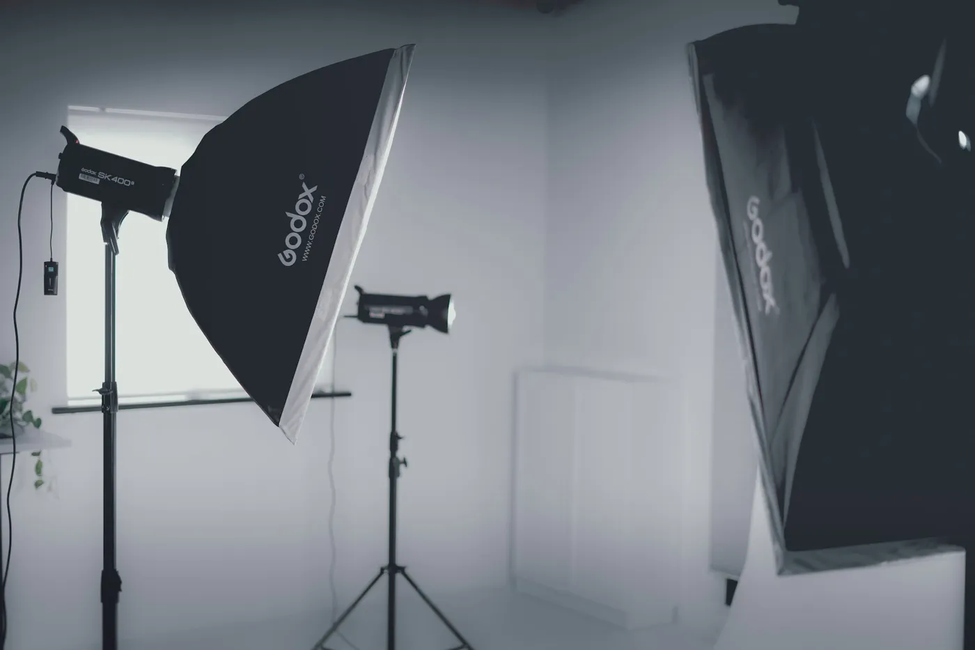 Studio lighting: two Godox softboxes and a flash on stands in a white room