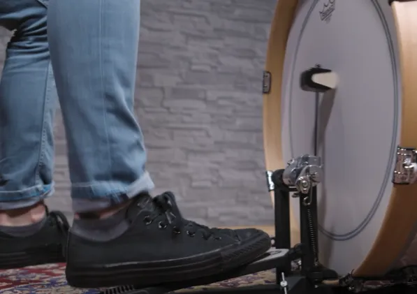 Close-up of a foot on the bass drum pedal, the beater hits the center of the head