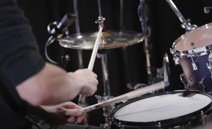 Close-up: right hand plays the hi-hat and left hand the snare, hi-hat about a hand span above the snare