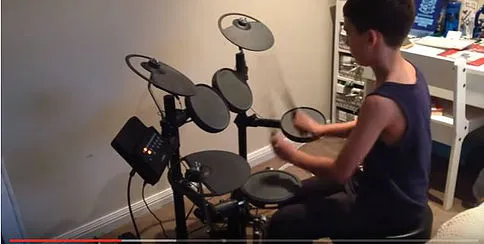 Young player at an e-drum kit: tom pads, snare and cymbals set within reach