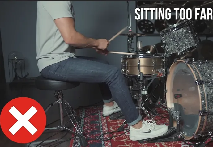 Wrong sitting position: drummer sitting too far from the kit (Sitting too far)