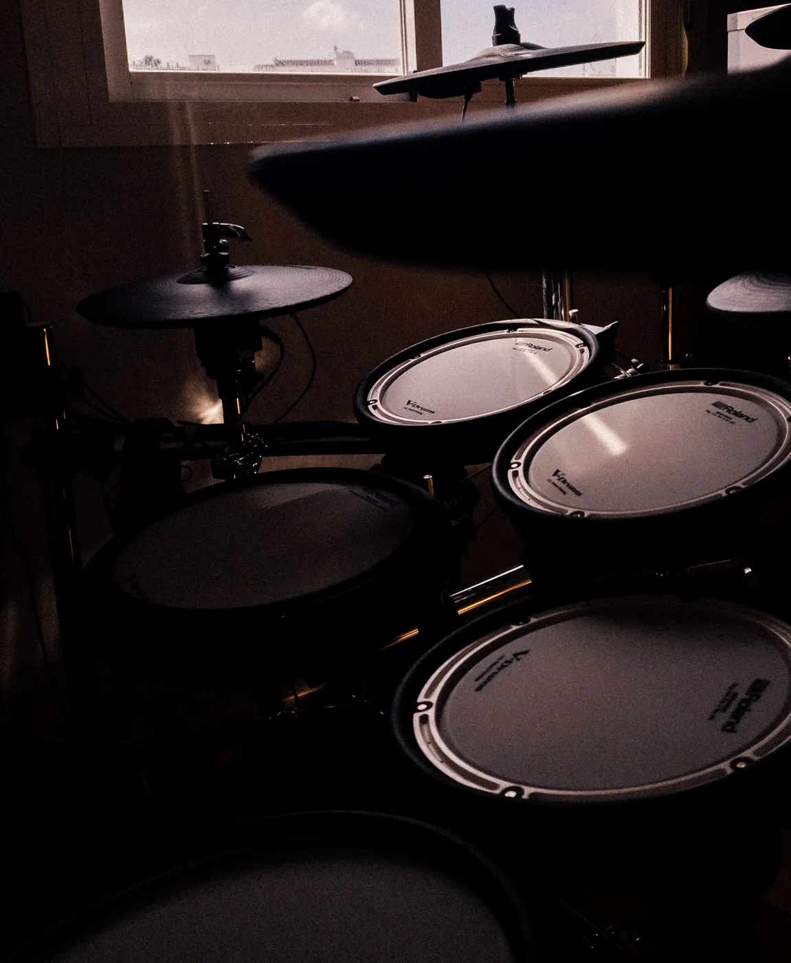 Roland electronic drums in a dim room: mesh head pads and cymbals