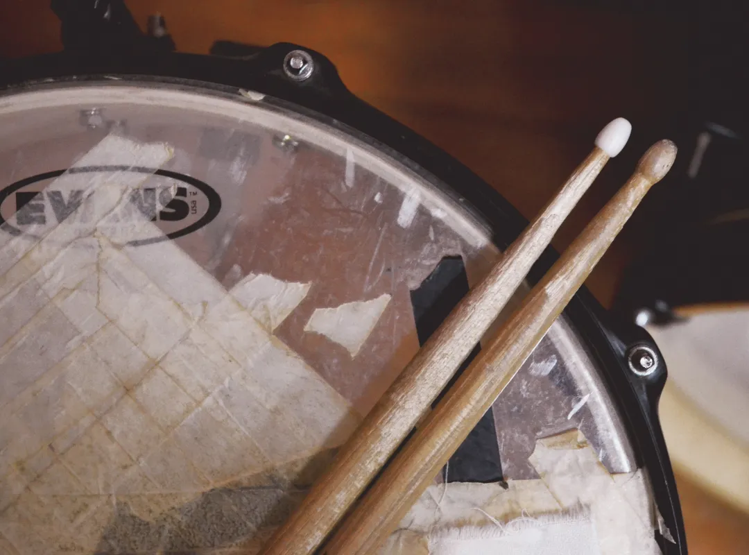 Worn and taped Evans snare head with two drumsticks on top