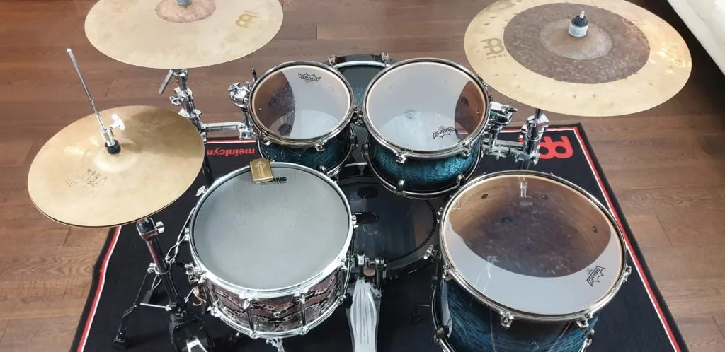 The cymbals of a traditional drum kit from above: hi-hat, two crashes and a ride on a Meinl rug