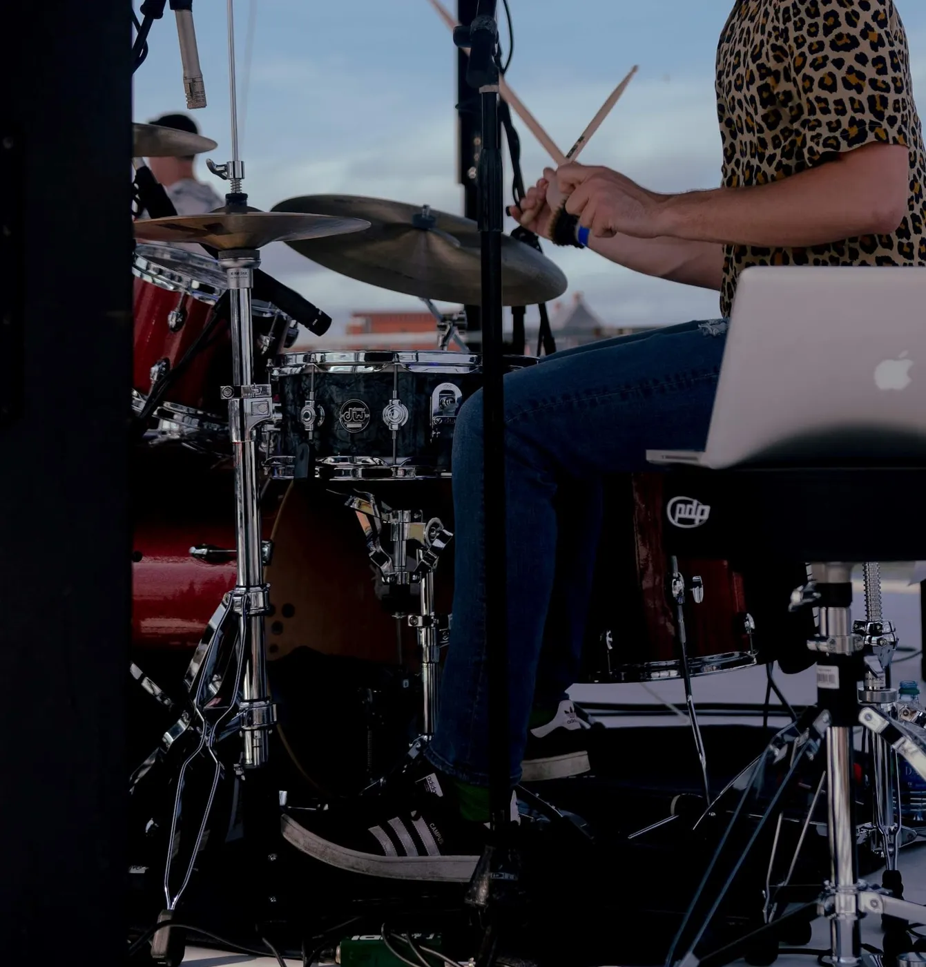 A drummer playing a kit on stage, with the hi-hat and crash in the foreground