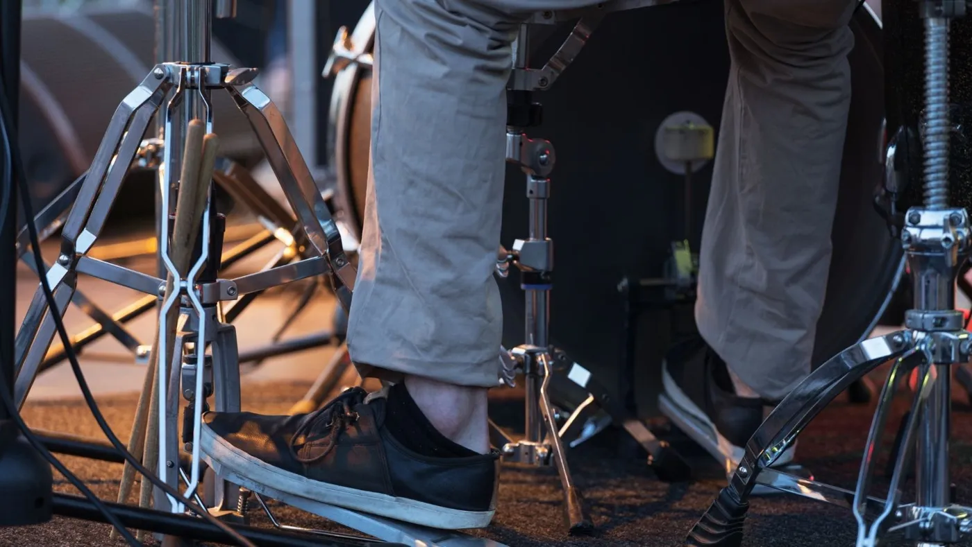 A drummer's feet on the bass drum and hi-hat pedals on stage