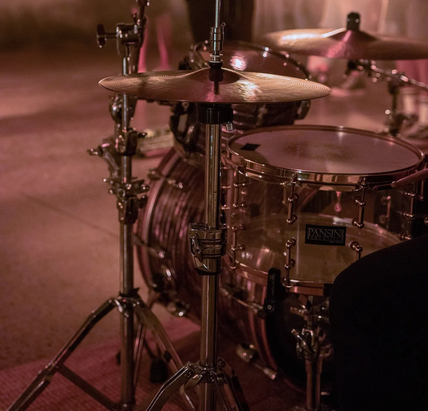 Close-up of a hi-hat stand and cymbals, with a clear snare and bass drum behind