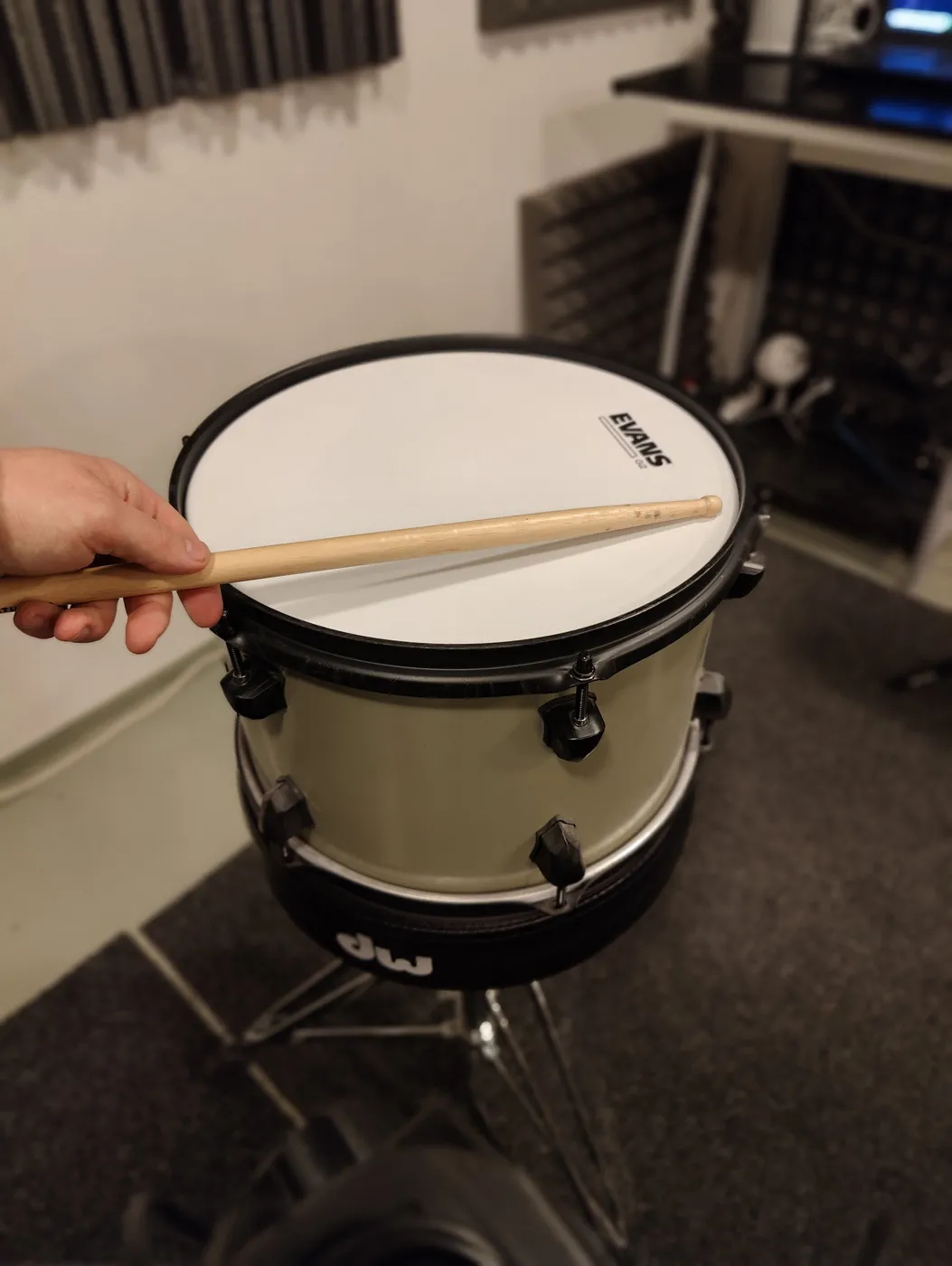 Tapping the head with a drumstick near a tension rod to check the tuning