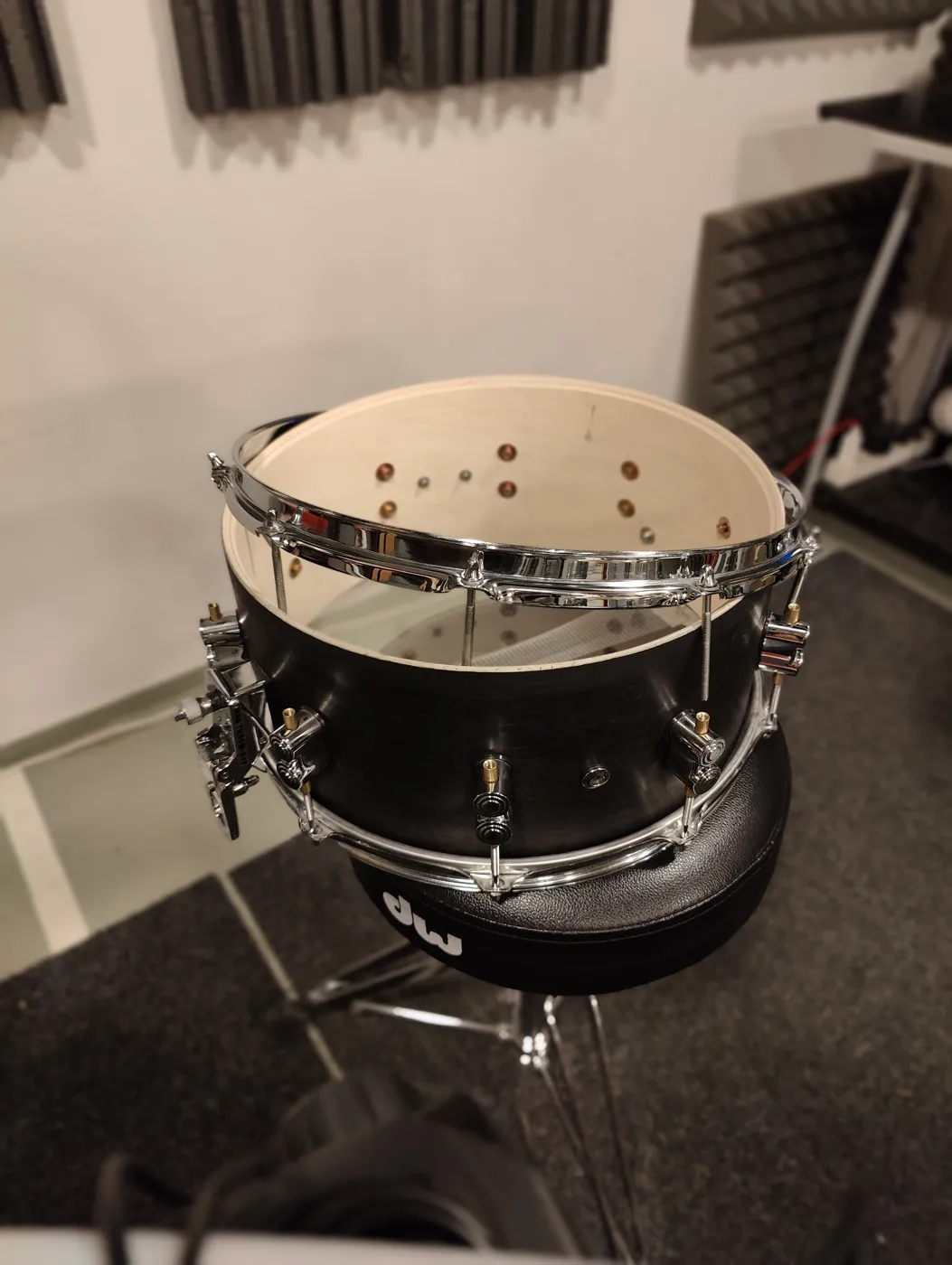 A snare without its bottom head, showing the inside of the shell and the hoop