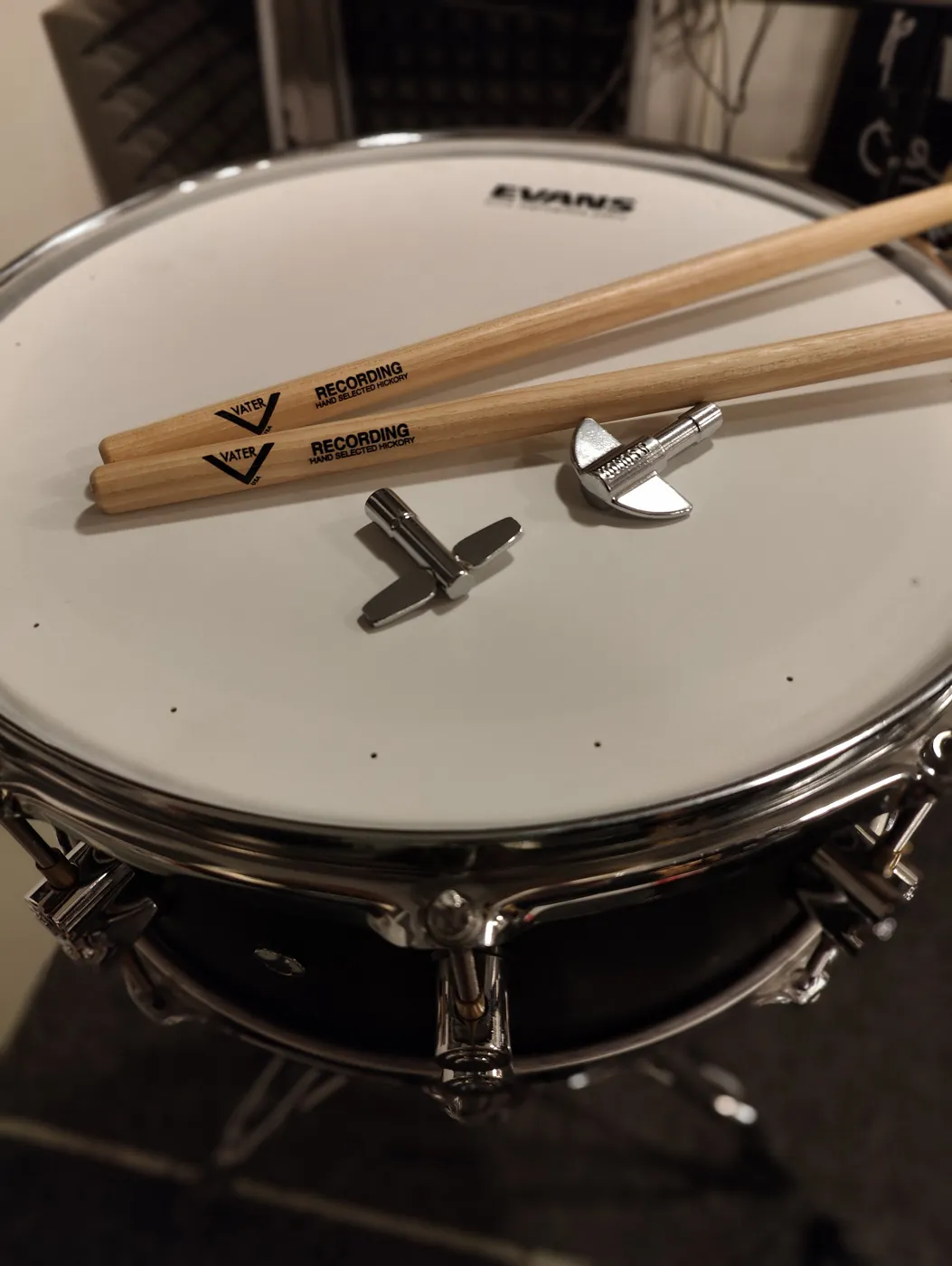 Drumsticks and two drum keys on top of a snare fitted with an Evans head
