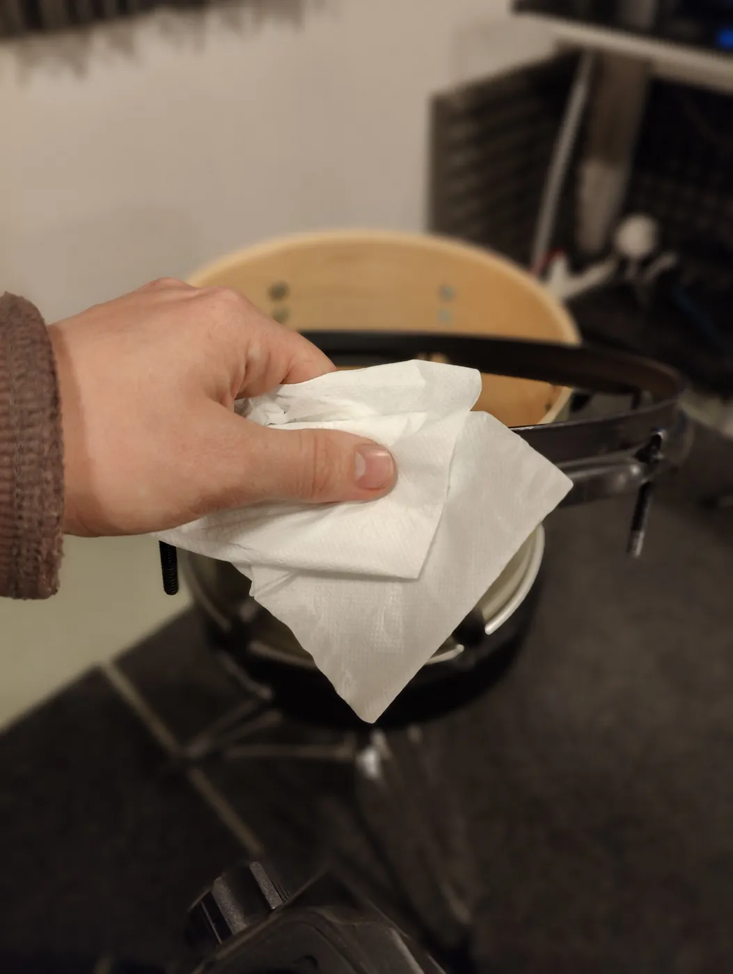 The tom's hoop being wiped clean with paper before tuning