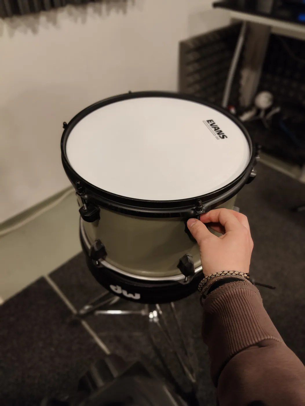 Tension rods being lightly tightened by hand before using a drum key