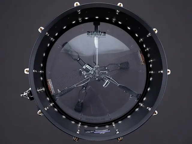 A snare seen from above through a clear resonant head, showing a dense row of tension rods