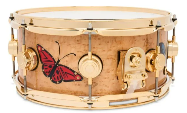 A wood snare with gold hardware and a red butterfly decoration